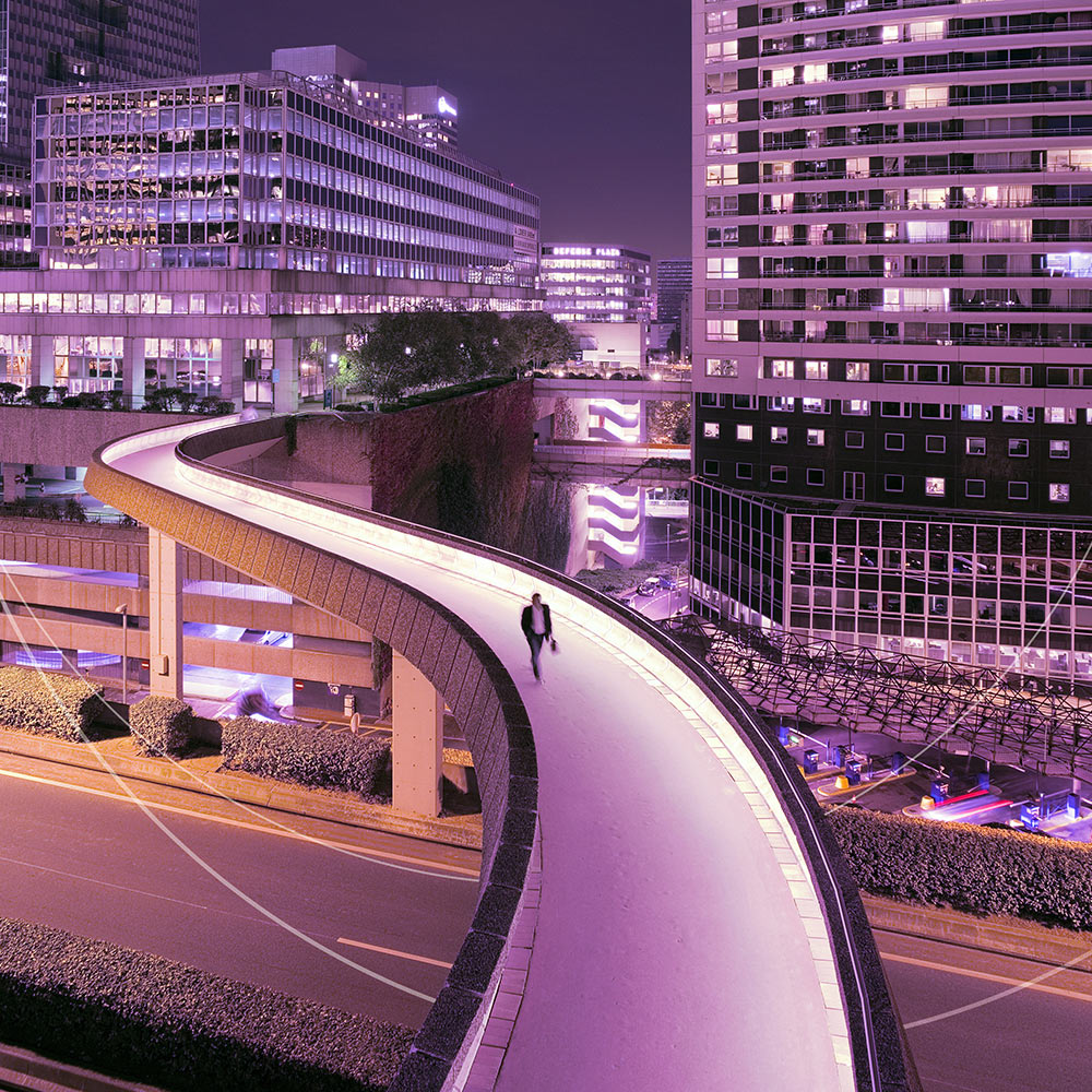 A person walking on a illuminated road in a city