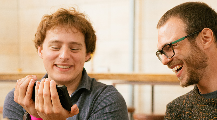 Google Cloud Team: Two men looking together at a phone and laughing