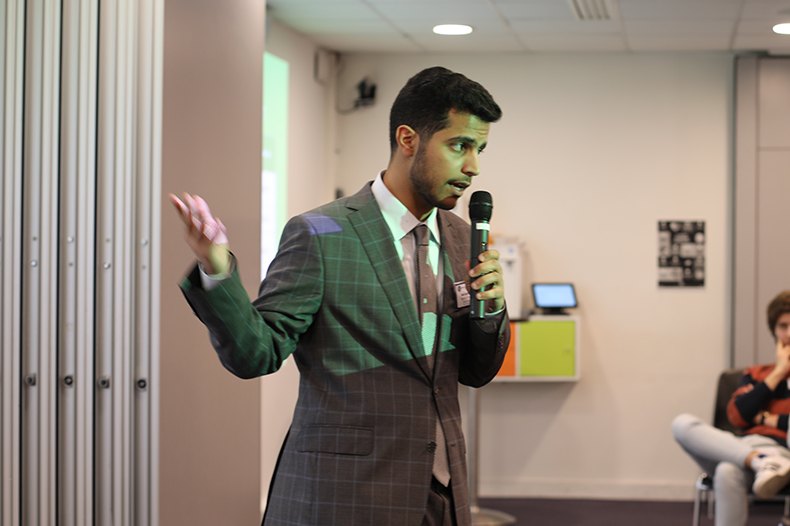 A man in a suit and tie passionately delivering a speech at a podium, engaging the audience with his words.