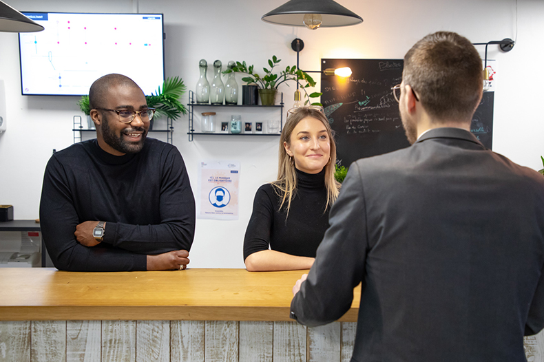 A man and woman sit at a counter, smiling and talking, capturing a cozy moment of companionship and laughter.