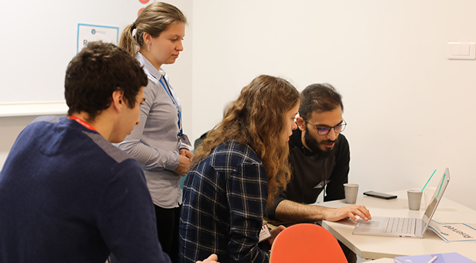 A varied group of individuals assembled at a table, each concentrating on the laptop while collaborating and exchanging ideas.