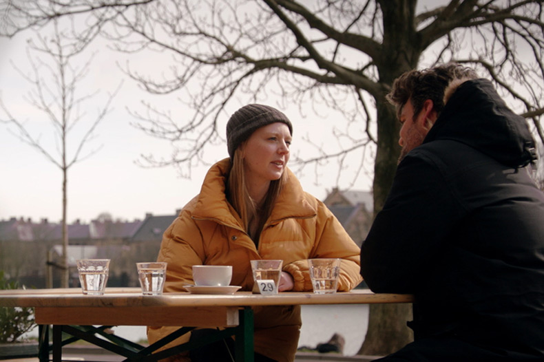 A man and woman enjoy coffee together at a cozy table, sharing smiles and conversation in a warm atmosphere.