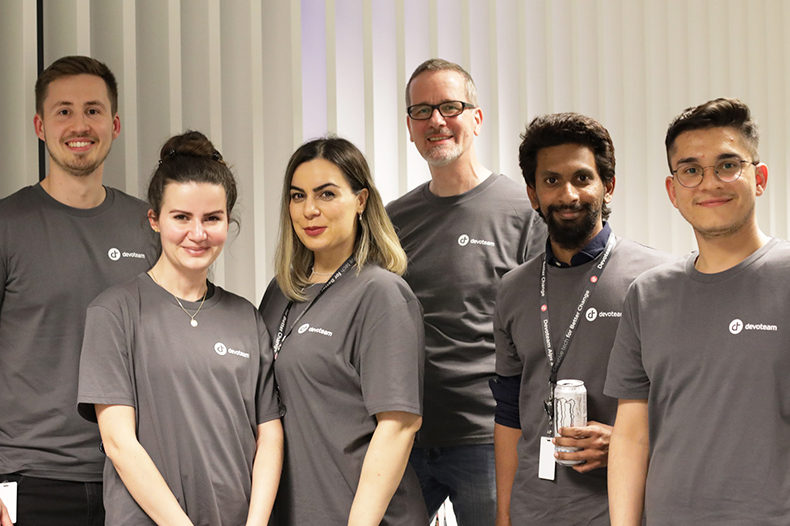 A cheerful group of people in grey shirts, posing together and showcasing a sense of unity and camaraderie.